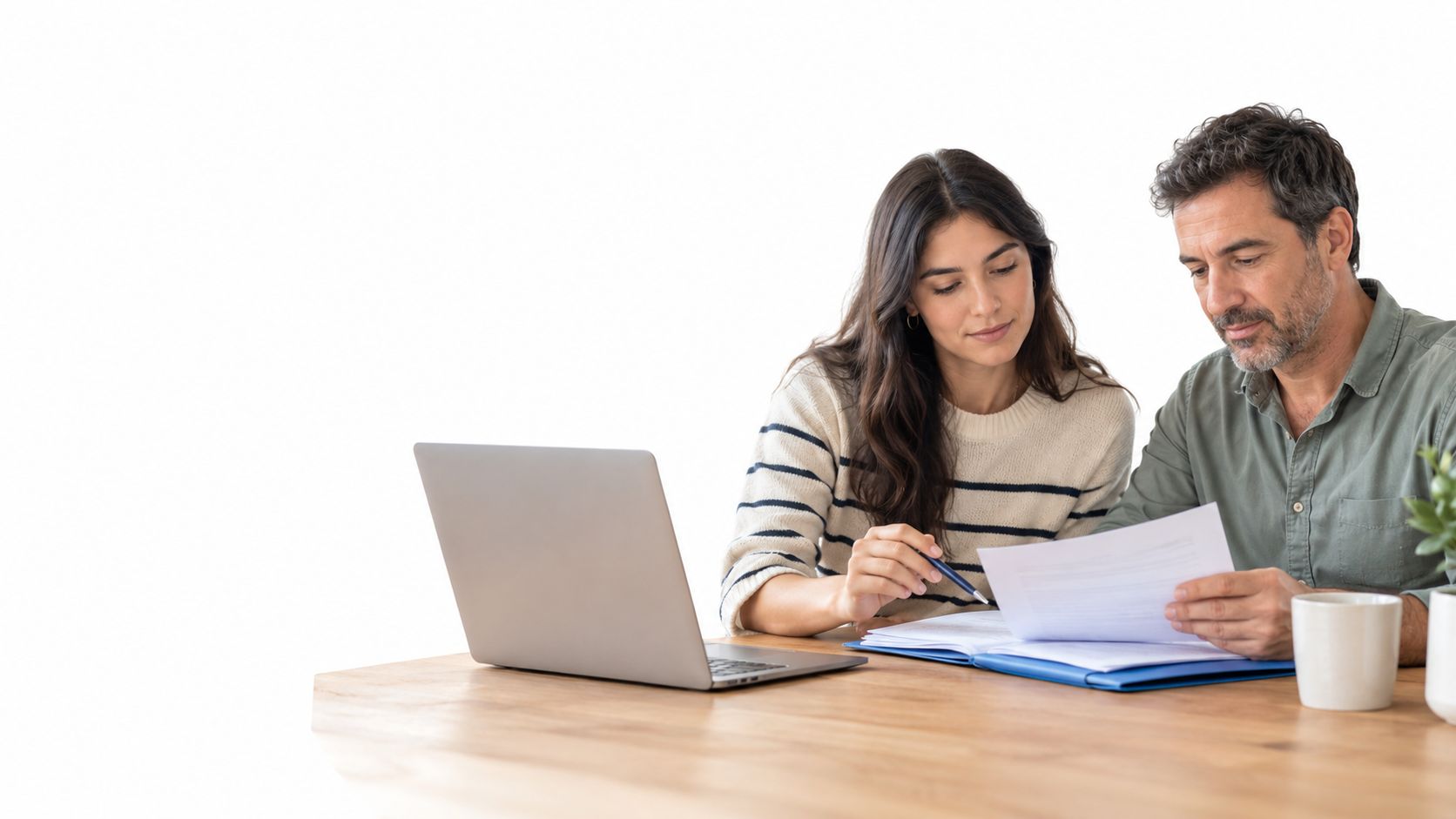 Una pareja revisando documentos importantes junto a una computadora portátil en una mesa de madera clara.